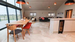 A spacious living area with a dining table, chairs, and a kitchen island. - Grange Barn (Shrewsbury)