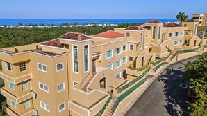A multi-story residential building with a curved facade, large windows, and a view of the ocean.