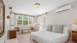 A bedroom with a large bed, a desk, a chair, and a window with curtains.