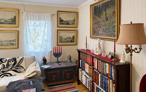 Ein gemütliches Wohnzimmer mit einer Couch, einem Bücherregal, einer Zierkommode und einem großen Gemälde an der Wand.