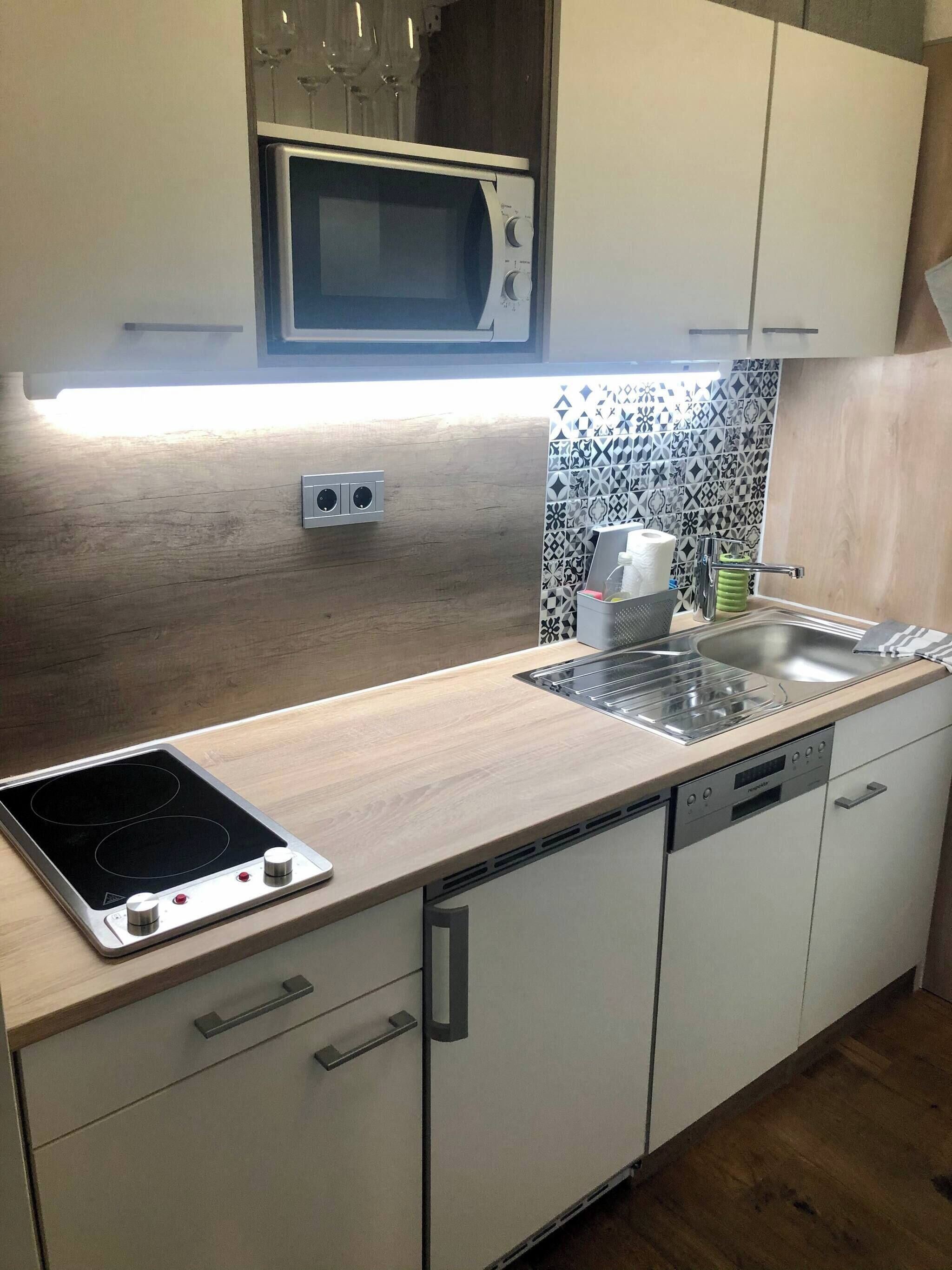 A modern kitchen with a microwave, stove, sink, and dishwasher.