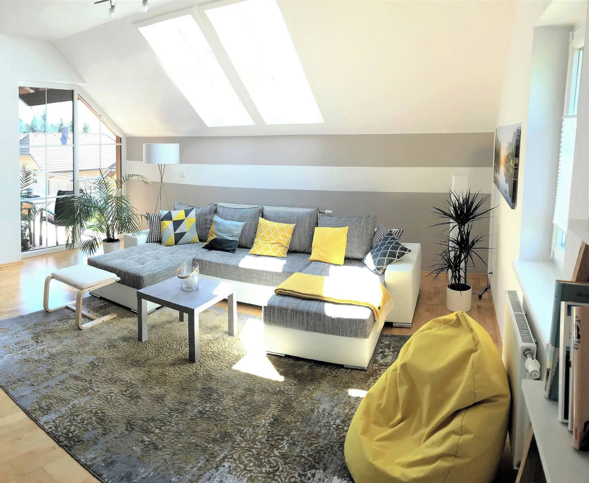 Una sala de estar moderna con un sofá gris, cojines amarillos, una mesa de centro blanca y un sillón de peluche amarillo.