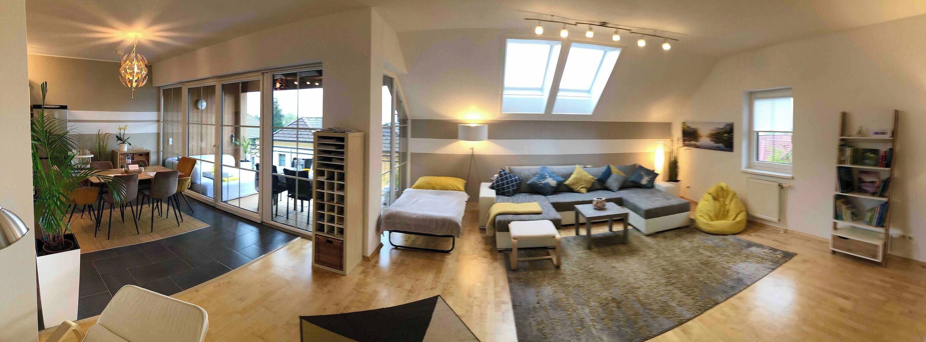 A modern living room with a sofa, coffee table, and a dining area with chairs and a table.