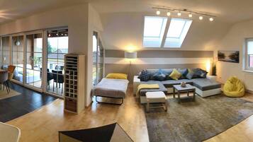 A modern living room with a sofa, coffee table, and a dining area with chairs and a table.
