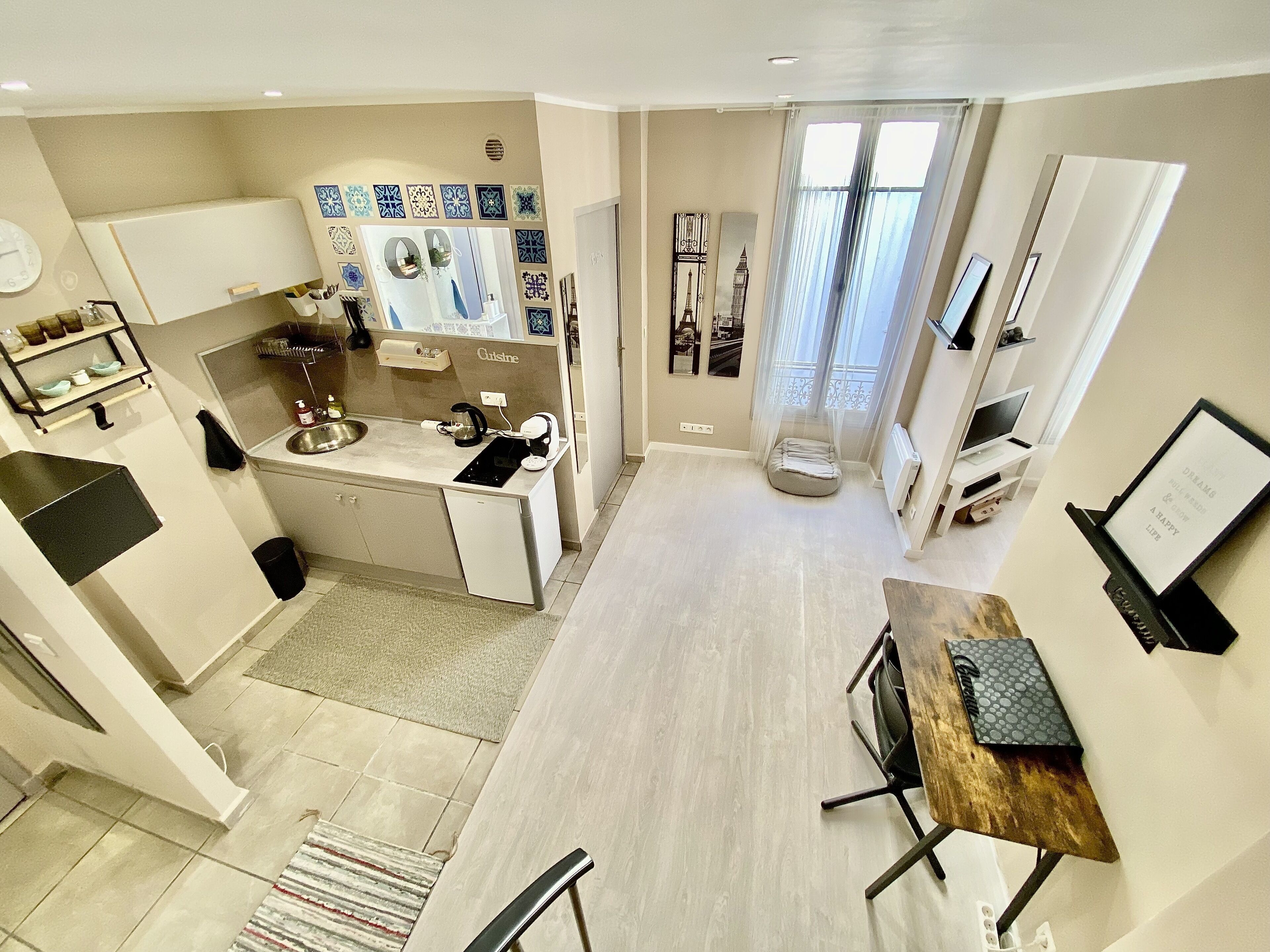 A compact kitchen with a dining area, a small seating space, and a view of the city through the window.