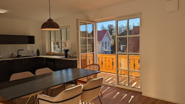 A modern kitchen with a dark countertop, white cabinets, and a hanging pendant light. - Liboria I Traumhafte Ferienwohnung am Riegsee mit Blick auf die Zugspitze! (Riegsee)