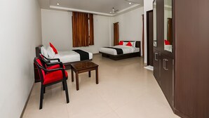 A modern hotel room with a sofa, two single beds, a wooden coffee table, and a wardrobe. - Club 7 (Bareilly)