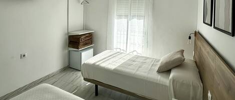 A minimalist bedroom with a bed, bedside table, and a mirror.