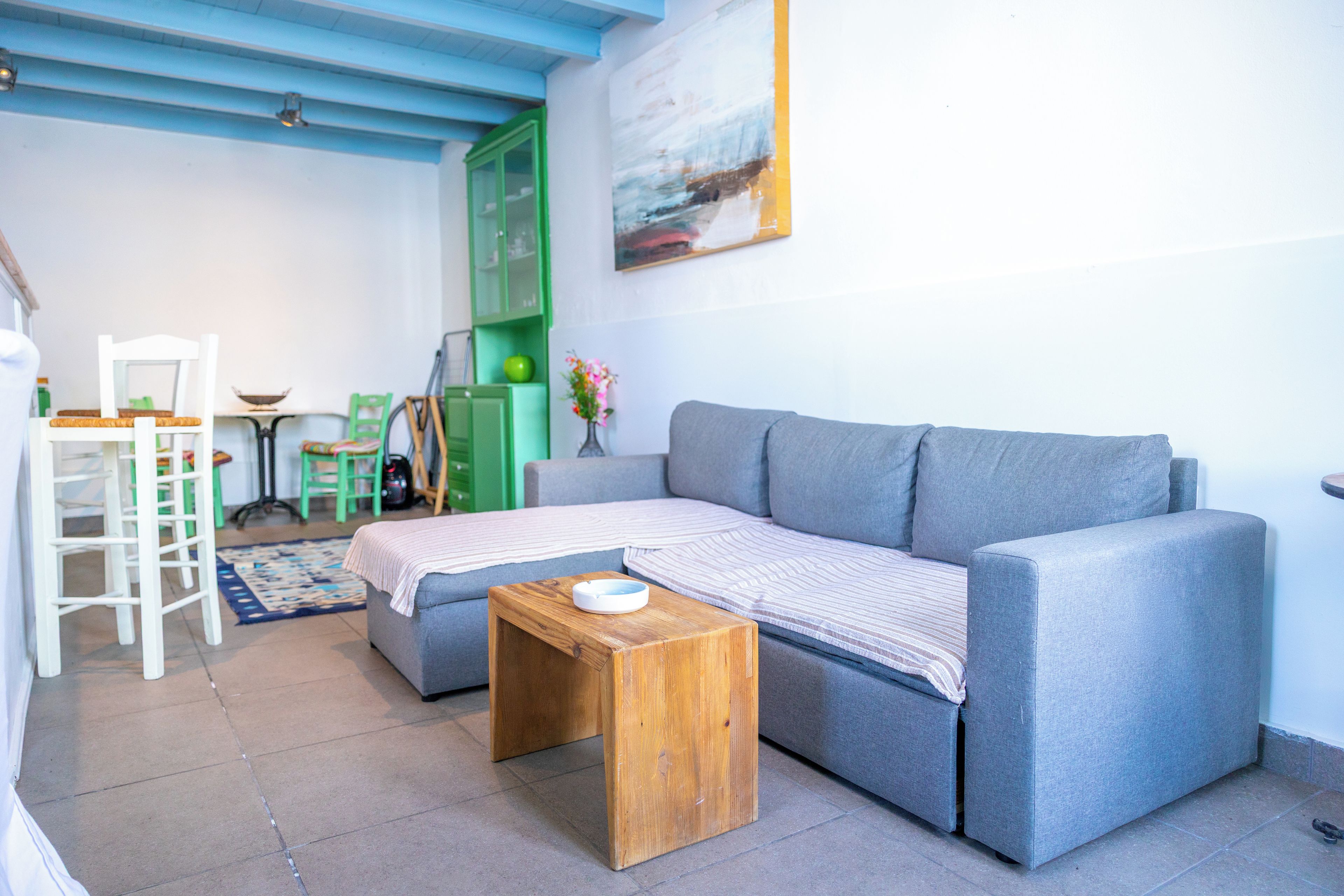 A living room with a grey sofa, a wooden coffee table, a green cabinet, and a painting on the wall.