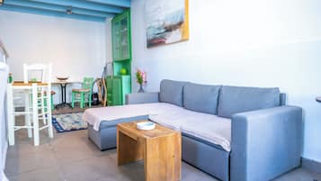 A living room with a grey sofa, a wooden coffee table, a green cabinet, and a painting on the wall.