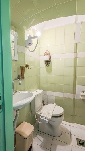 A bathroom with a sink, toilet, and a hairdryer mounted on the wall. - Pitini 1 - Seafront - Harbour view (Symi)