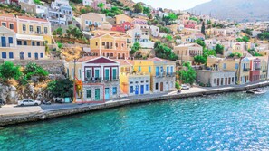 A coastal town with colorful buildings, a clear blue waterfront, and a stone wall along the sea.