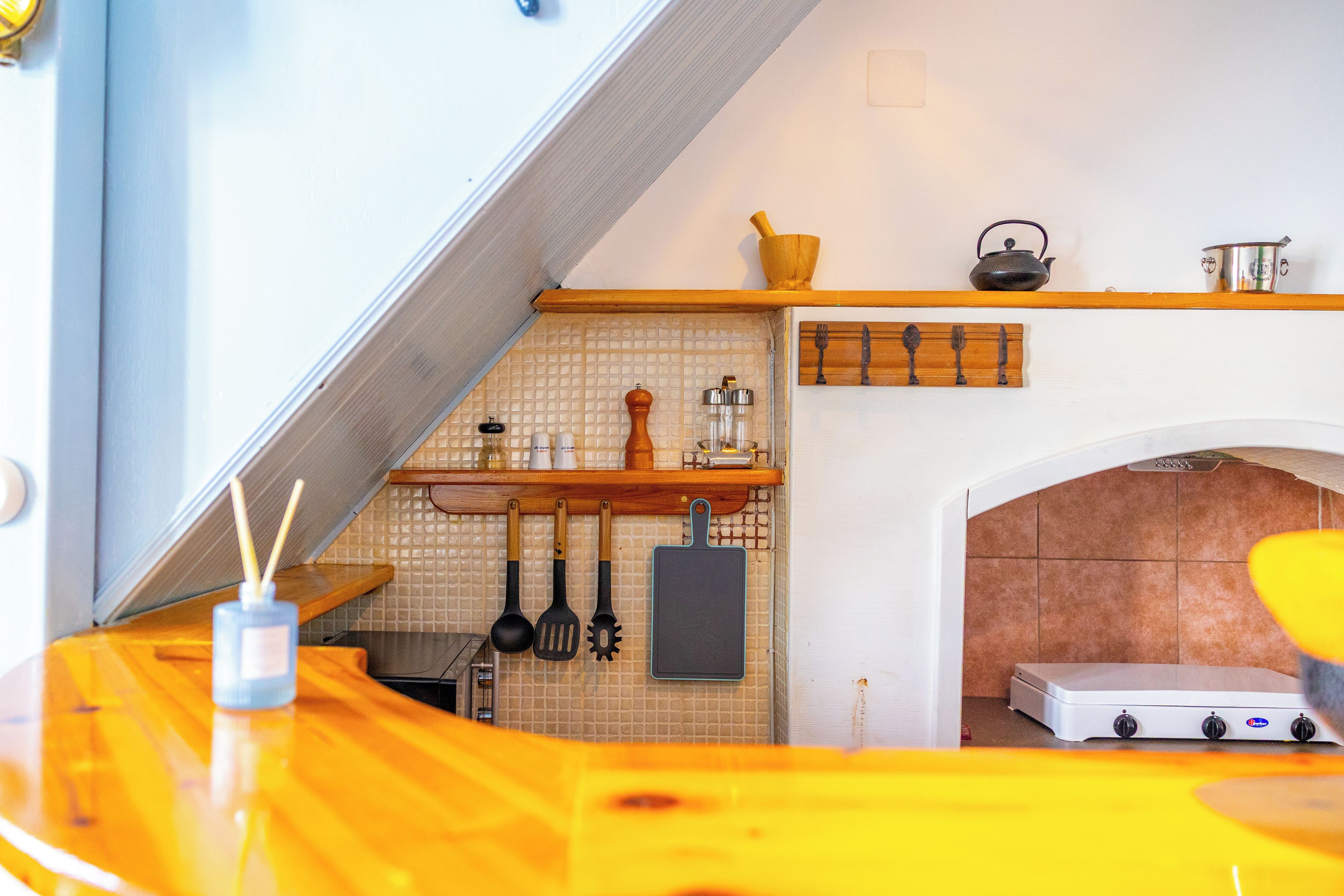 Una cocina con encimera de madera, utensilios colgantes, un hervidor y una estufa.
