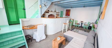 A compact living space with a kitchenette, a sofa, a dining table, and a staircase.