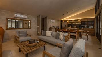 Uma sala de estar moderna com sofá, cadeiras, mesa de centro e área de cozinha com balcão.