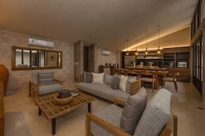 A modern living room with a sofa, chairs, a coffee table, and a kitchen area with a bar.