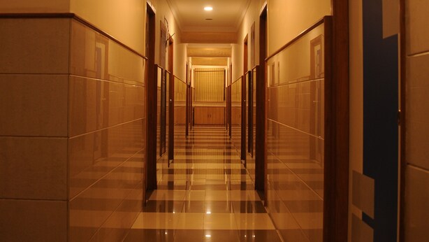 A long, well-lit hallway with checkered flooring and doors on both sides. - Srinidhi Residency (Bengaluru)