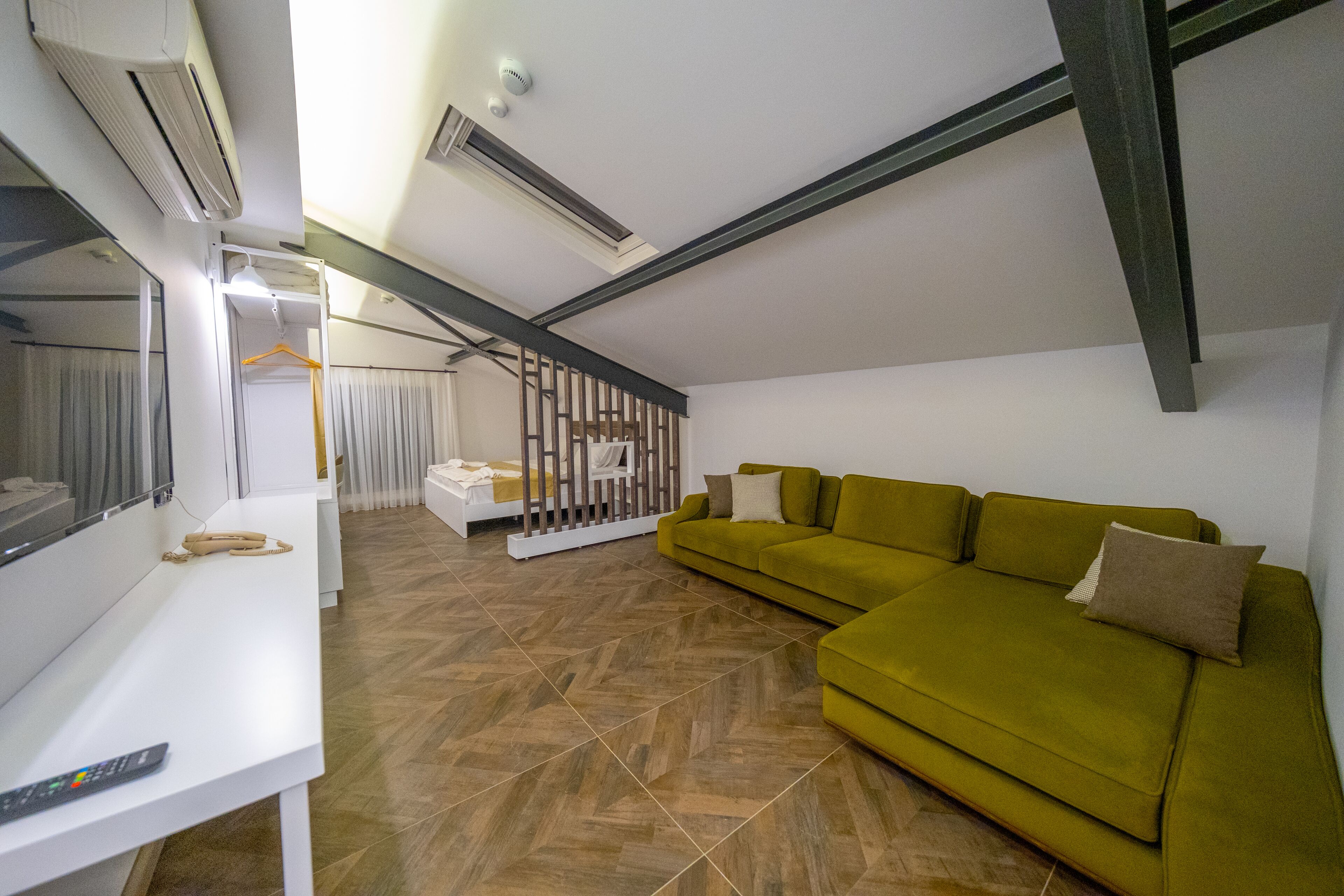 Uma sala de estar moderna com um sofá verde, uma escrivaninha branca e uma escada que dá para um andar superior.