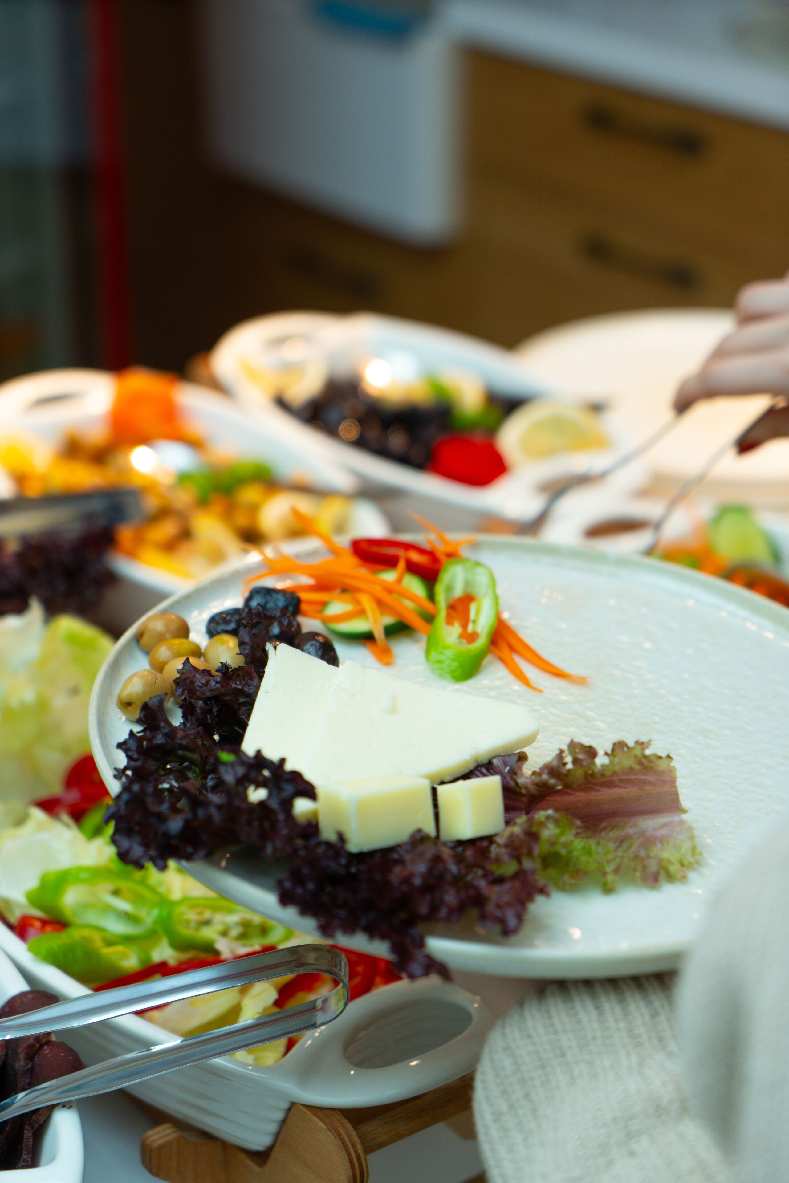 A buffet table with various dishes, including salads and a cheese platter.