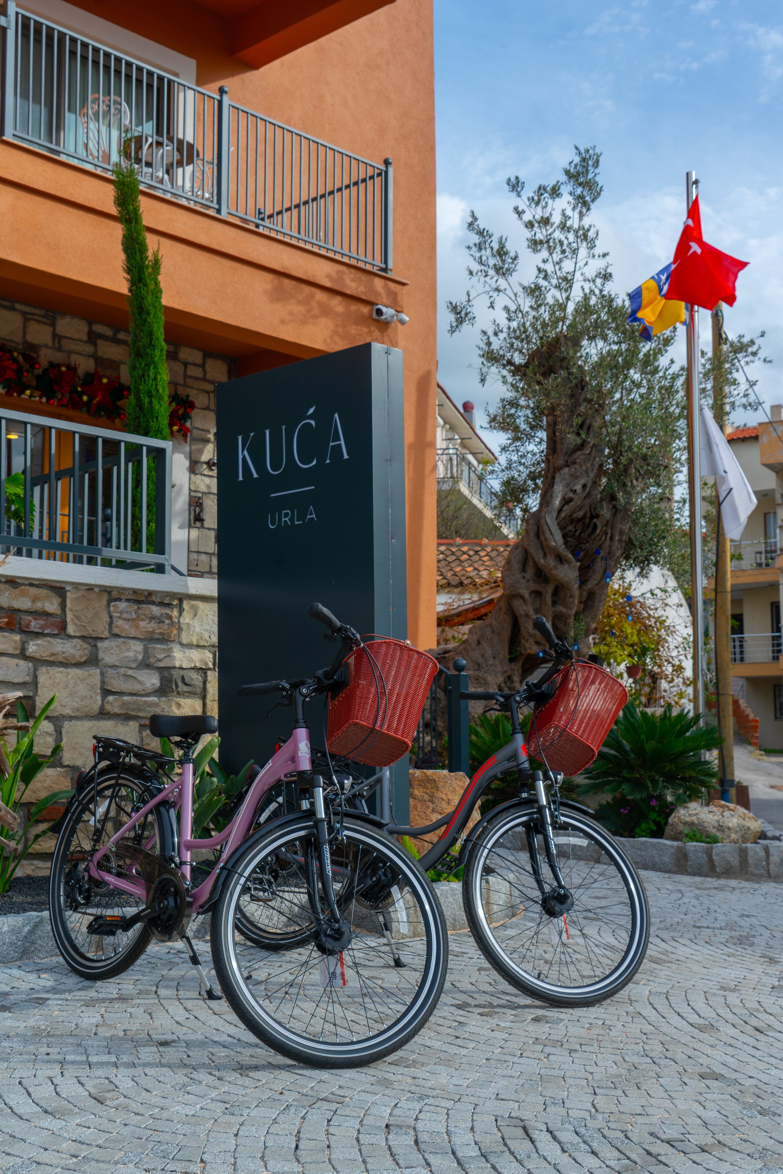 Um edifício com uma placa que diz "KUÇA URLA" e duas bicicletas estacionadas na frente.