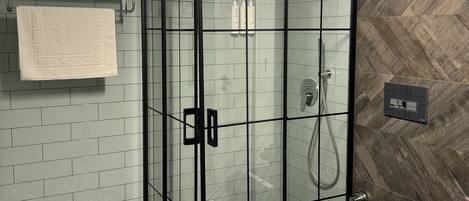 A modern bathroom with a glass-enclosed shower, a black toilet, and a patterned floor.
