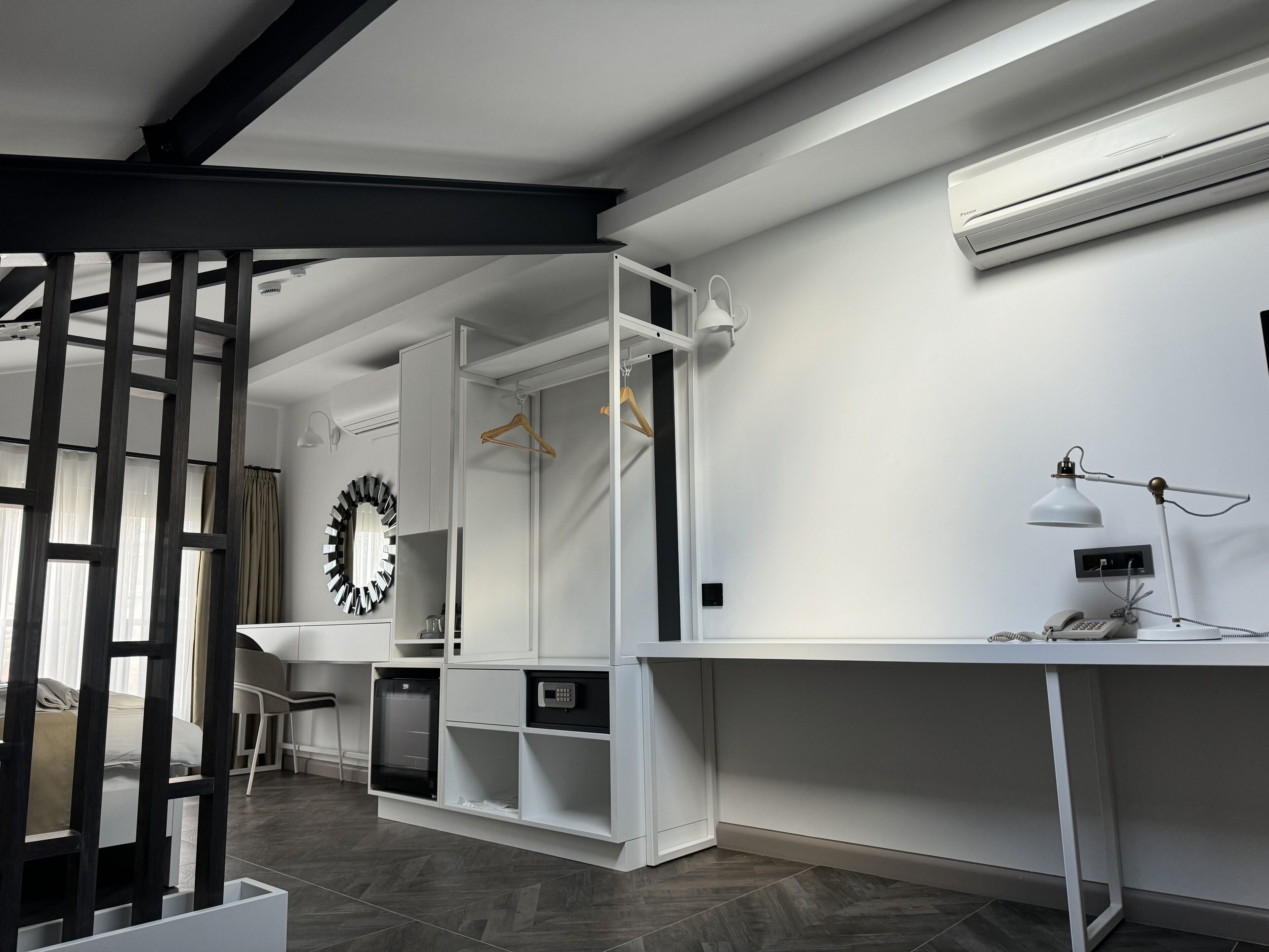 A modern hotel room with a desk, wardrobe, and a large mirror.