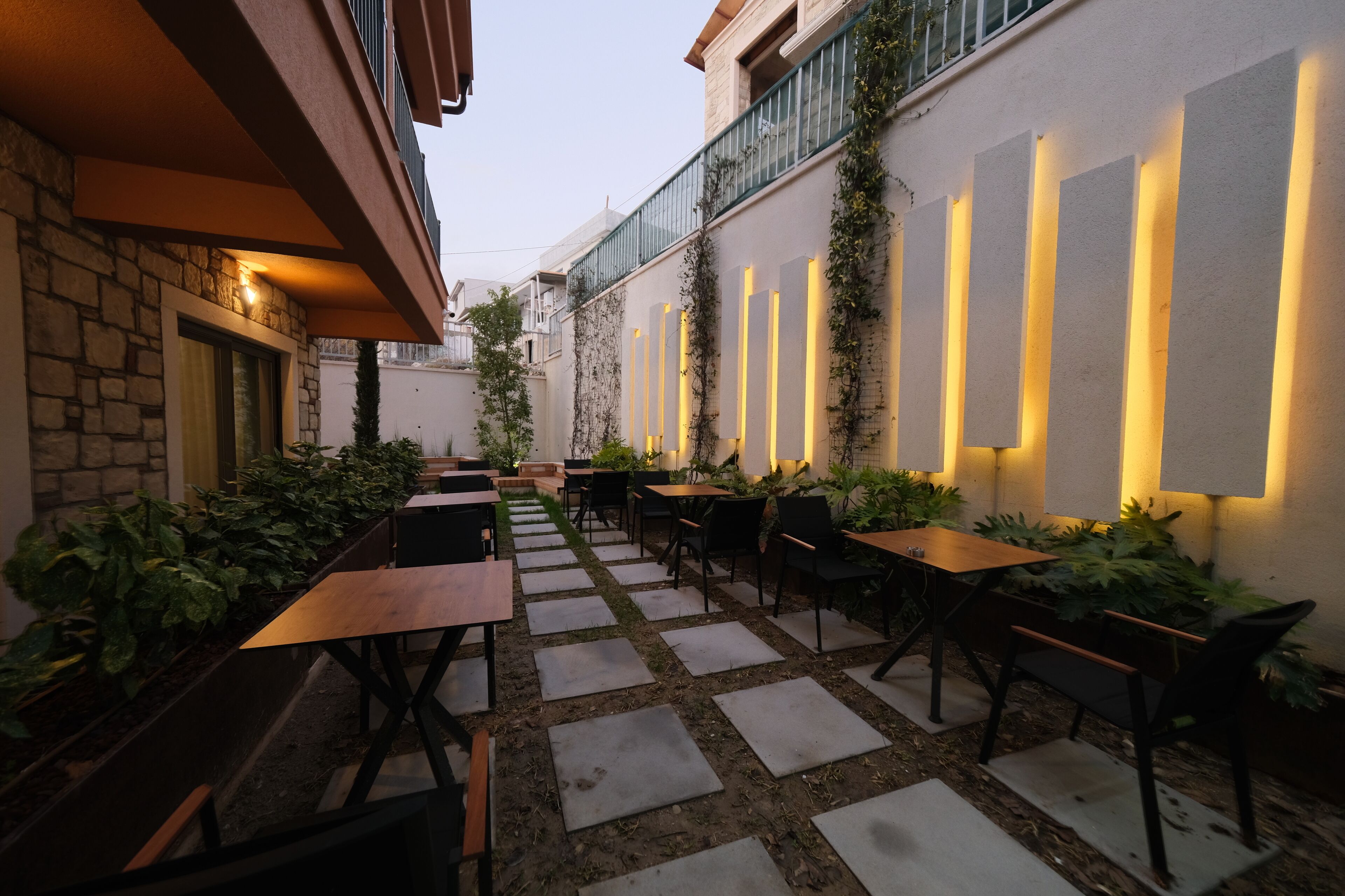 An outdoor patio area with stone flooring, wooden tables, and chairs.
