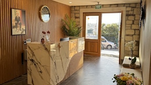 A reception area with a marble counter, wooden paneling, a clock, and a view of the outside. - KUCA URLA (Urla)