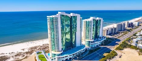 A high-rise hotel with a modern design, located near a beach with a clear view of the ocean.