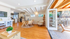 Un vaste espace de vie doté d’un plancher en bois, d’une table à manger avec des chaises, d’un canapé et d’un mur en pierre.