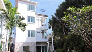 Una casa moderna de dos pisos con fachada de piedra, un balcón y un césped bien cuidado.