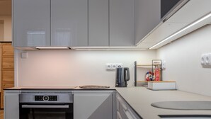 Een moderne keuken met grijze kastjes, een inbouwoven, een koffiezetapparaat en een kleine koelkast.