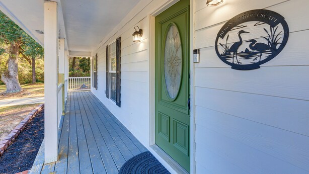 A porch with a green door, a decorative emblem, and a railing. - Tranquil Coden Retreat: 10 Mi to Dauphin Island! (Theodore)