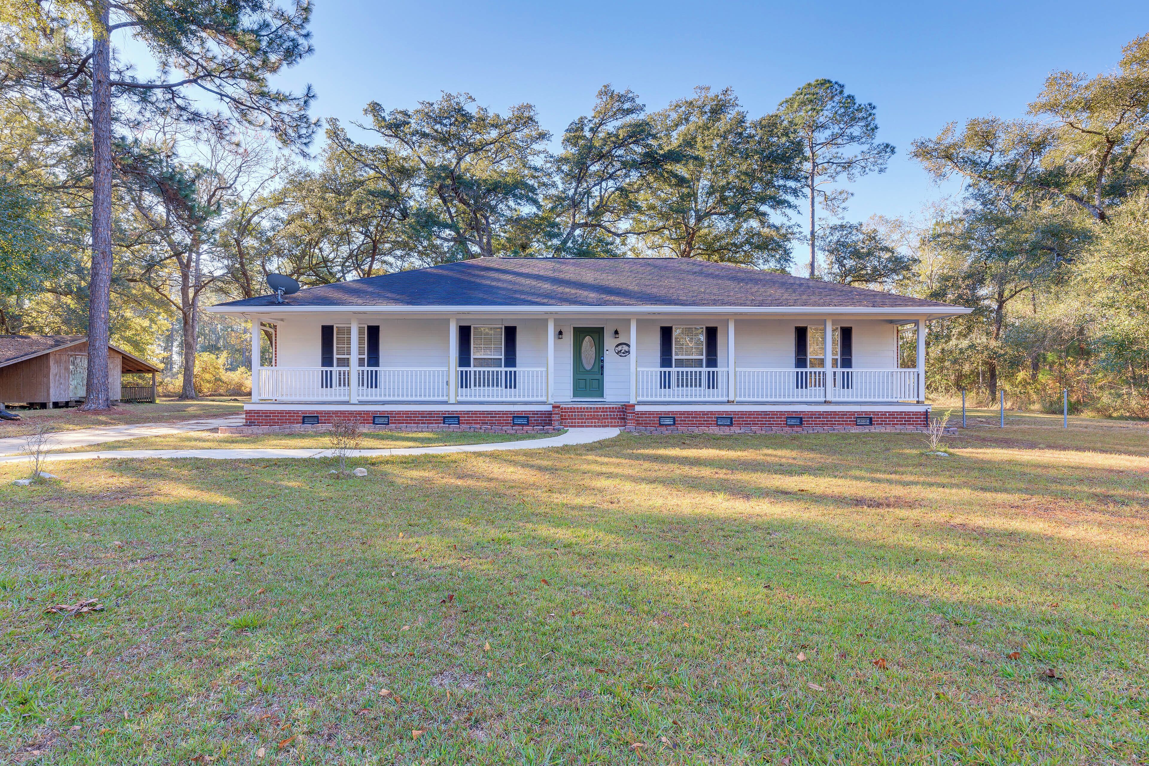 A two-story house with a front porch, brick foundation, and a green door.