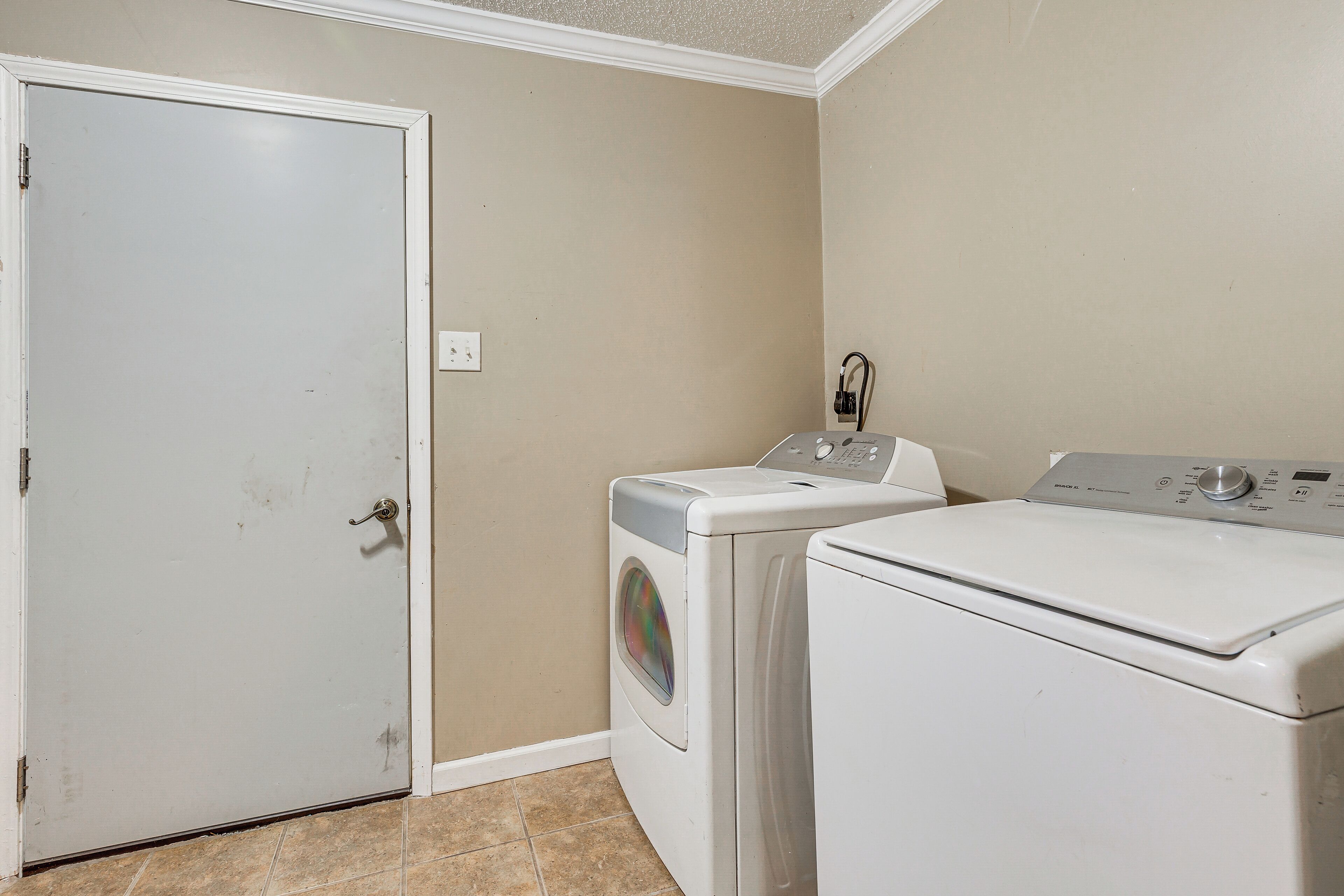 A laundry room with a door, a washing machine, and a dryer.