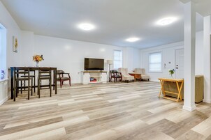 Una sala de estar amplia con piso de madera, televisor, chimenea y un comedor con sillas y una mesa.