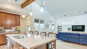 A modern kitchen with wooden cabinets, a large island, and pendant lighting. - Flagstaff Home w/ Fire Pit + Hiking Trail Access! (Flagstaff)