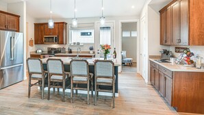 A modern kitchen with wooden cabinets, stainless steel appliances, and a central island with chairs. - Flagstaff Home w/ Fire Pit + Hiking Trail Access! (Flagstaff)