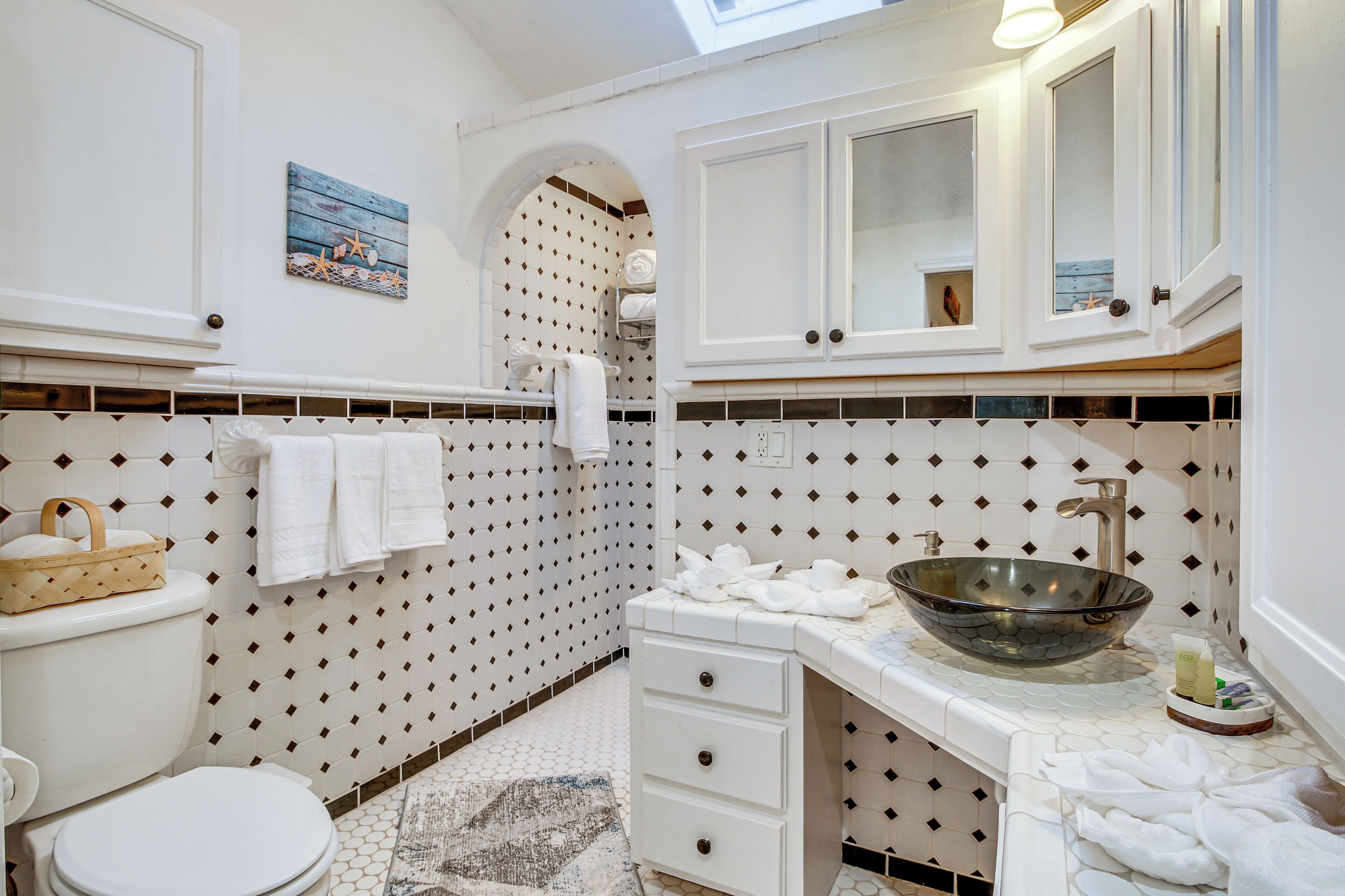 A bathroom with a white sink, a large mirror, and a tiled backsplash.
