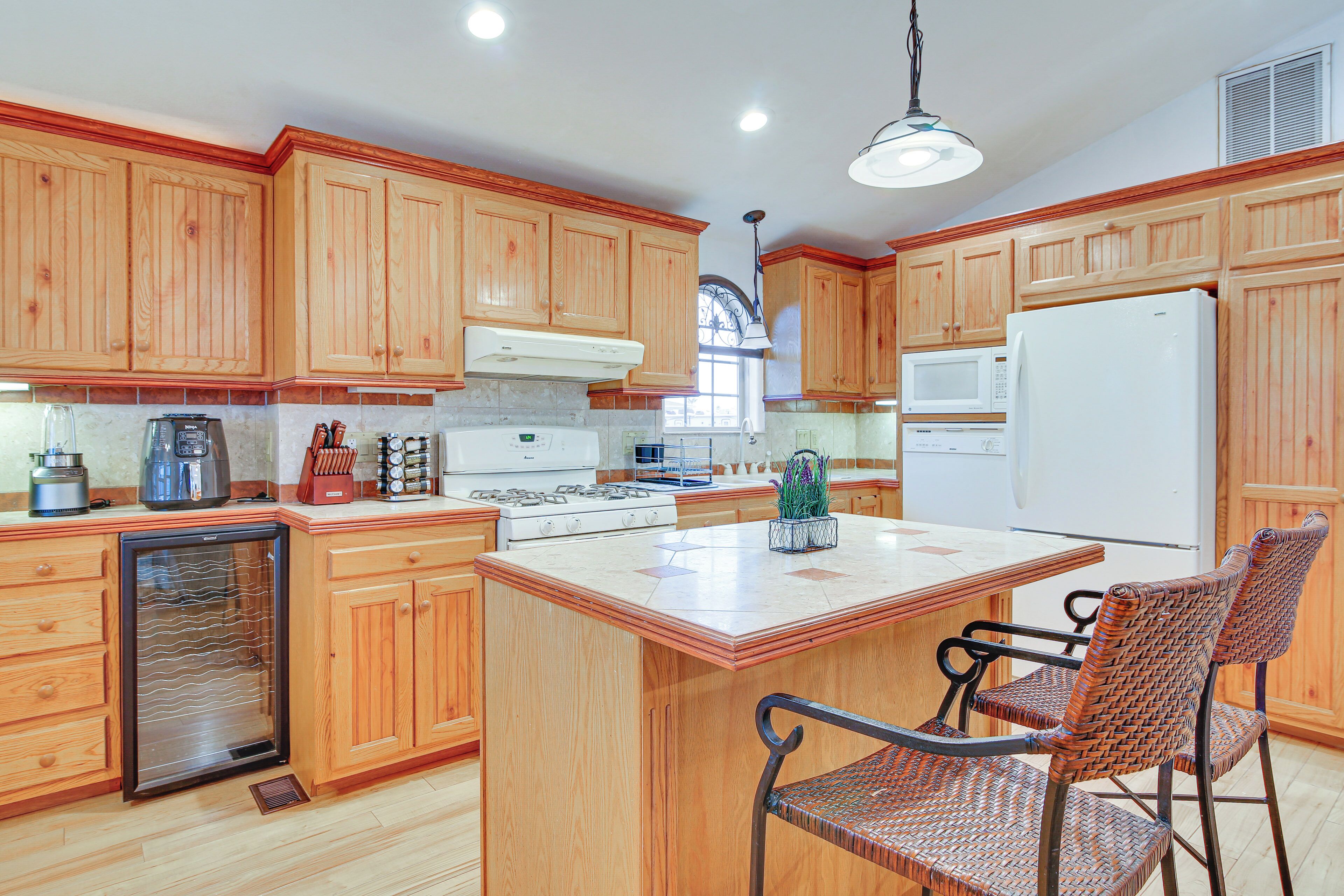 A kitchen with wooden cabinets, a refrigerator, a microwave, a stove, and a sink.
