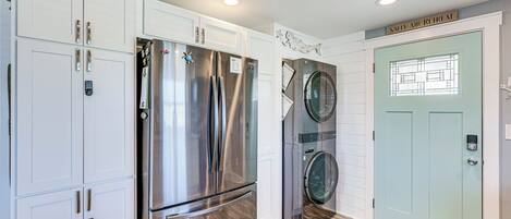 A modern kitchen with stainless steel appliances, white cabinetry, and a green door with a welcome mat.