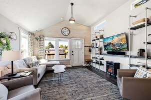 A cozy living room with a sofa, chairs, a fireplace, and a large painting on the wall.