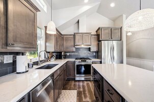 A modern kitchen with dark wood cabinets, stainless steel appliances, and a white countertop.