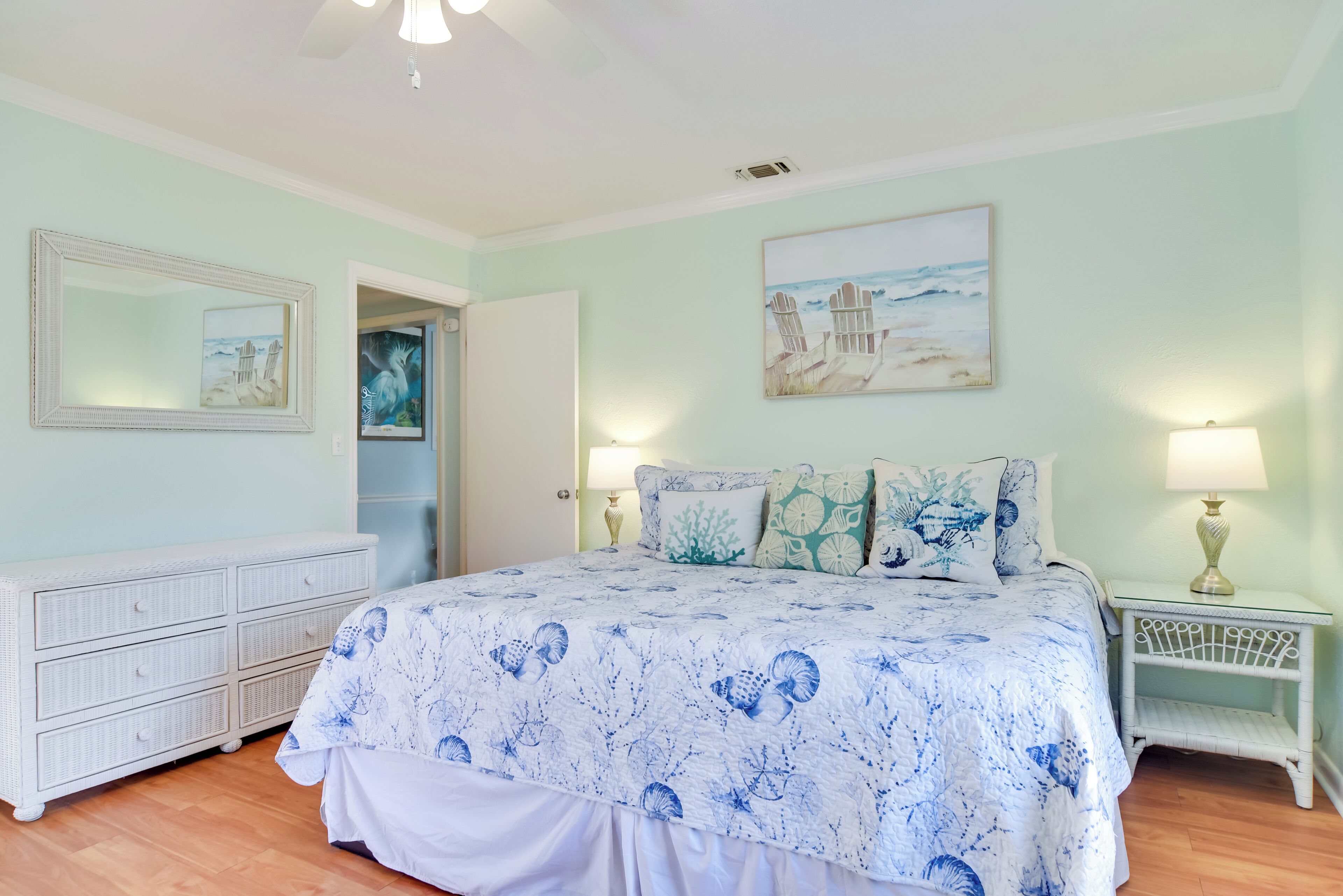 A bedroom with a bed, a dresser, a nightstand, and wall art.