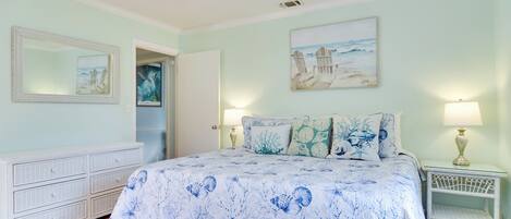 A bedroom with a bed, a dresser, a nightstand, and wall art.