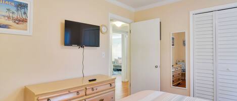 Un dormitorio con cama, cómoda, televisor montado en la pared y armario.