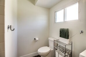 Bathroom features a toilet, window, and storage shelf.