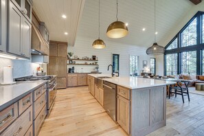 A spacious kitchen with wooden cabinets, a central island, and pendant lighting. - Luxury Broken Bow Cabin w/ Hot Tub on 3 Acres! (Broken Bow)