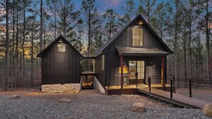 Une cabane avec des fondations en pierre, un revêtement extérieur en bois et une porte d’entrée en verre.