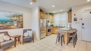A modern kitchen with wooden cabinets, a built-in oven, and a dining area with a bar stool. - Pismo Beach Vacation Rental - Walk to Town & Ocean (Pismo Beach)